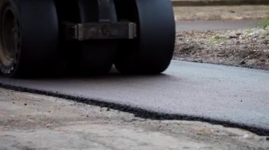 Ağır titreşimli paten sıkıştırıcılı asfalt yol silindiri bir yol inşaatındaki yolda yeni bir sıcak asfalta bastırıyor. Asfalt kaldırımda ağır titreşimli silindir çalışıyor. Onarılıyor