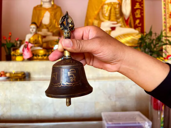 stock image Buddhist bells hanging in temple, Hand ringing small bell inside temple, Buddhist in traditional robes ringing temple bell surrounded by peaceful garden setting