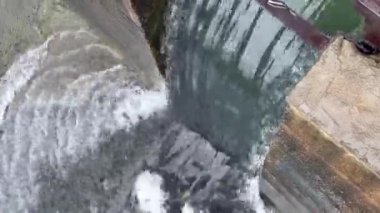 Su akışı, baraj duvarından basınçlı su çıkışı, boru hattı suyu, fabrika endüstrisi, su dalgaları, bir sürü beyaz köpük ve baloncuk.
