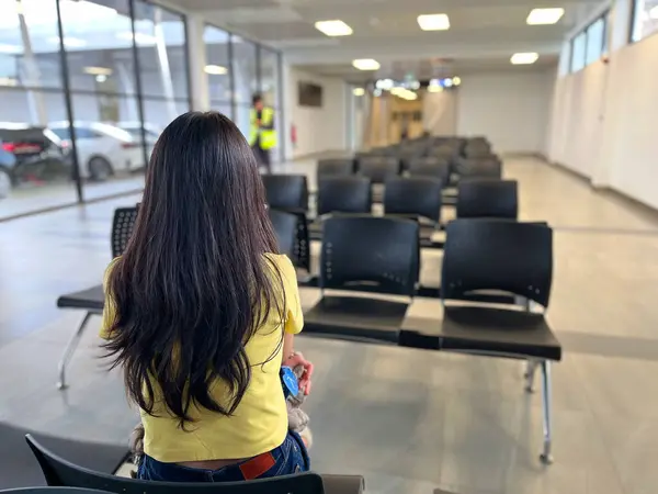 stock image a woman sitting in an airport terminal, featuring stylish shoes and a row of modern black chairs, minimalist setting emphasizes the clean design, calm atmosphere, airport interiors, modern lifestyle