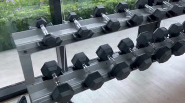 Modern bir spor salonundaki bir askıya düzgünce yerleştirilmiş 25 kiloluk altıgen dambıllar, doğrusal bir şekilde yerleştiriliyor, simetri ve düzen hissi yaratıyor. En yakın dambıl üzerinde yoğunlaşacağız.