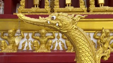 Geleneksel bir Tayland tapınağının süslü mimarisinin bir parçası olan güzel, karmaşık bir altın Naga yılan heykeli. Naga 'nın kafası, Tayland' ın kültürel ve dini mirasıyla süslenmiş.