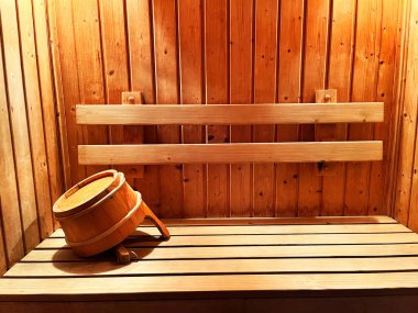 Geleneksel ahşap sauna. Doğal ahşap dokuları ve ahşap kovasıyla fotoğraf, huzurlu bir ortam sunuyor. Rahatlama ve refah için mükemmel bir ortam.