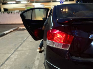 parked black car with its rear door open and red brake lights illuminated. The car is parked on a street at night, with some exterior lighting in the background, car on the road, car emergency clipart