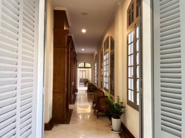 Klasik ahşap mobilyalar, geniş kemerli pencereler ve yumuşak ortam aydınlatma ile zarif koridor sıcak ve davetkar bir atmosfer yaratıyor ahşap mobilyalar, kemerli pencereler ve sıcak bir atmosfer oluşturan klasik koridor.