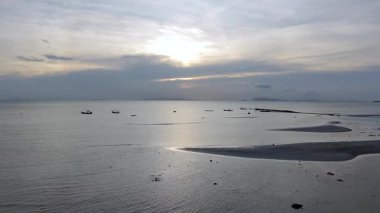 Koh Samui, Tayland 'da gün batımında sakin bir plaj. Sakin deniz gökyüzünün altın renklerini yansıtırken, küçük balıkçı tekneleri sakin su, doğa ve huzurlu kıyı manzaraları üzerinde yüzüyor.