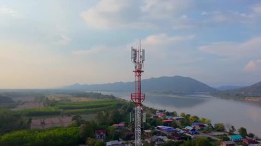 Telekomünikasyon kulesi, günbatımında bir telekomünikasyon kulesinin havadan görünüşü arka planda kırsal manzara, kablosuz iletişimi ve kırsal altyapıyı sembolize ediyor.