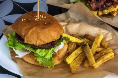 Sulu ve ağız sulandıran sığır burger arasında taze yumuşak çörek ile marul ile kızarmış patates kızartması ile servis edilir.