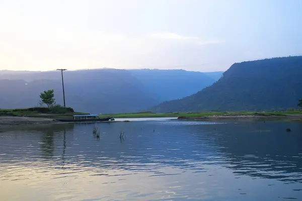 Yeşil Tepe, mavi gökyüzü, tekne ve nehir manzarayı güzelleştiriyor.
