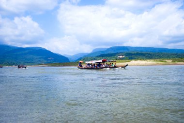 Sylhet, Bangladeş 'teki bir nehrin sakin sularında usulca gezinen geleneksel bir teknenin huzurlu ve resimli bir sahnesi.. 