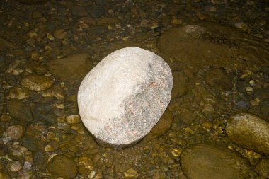 This striking photograph features a large, imposing stone partially submerged in calm, crystal-clear water.  clipart