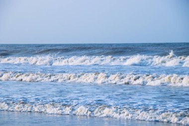 Güçlü okyanus dalgalarının kumlu bir sahile çarpmasının büyüleyici görüntüsü dramatik bir doğa gücü yaratıyor.. 