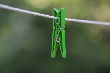 Yeşil elbise askısı beyaz çamaşır ipinde bulanık doğa arkaplanı.