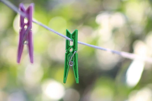 Clothes pegs, selective focus on green clothes peg on white clothesline.