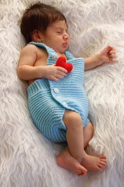 Tatlı Bebek Beyaz Pofuduk Battaniyenin Üzerinde Uyuyor Elinde Küçük Kırmızı — Stok fotoğraf