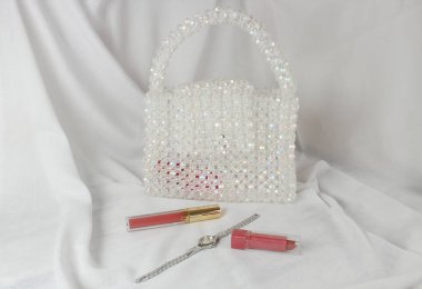 El yapımı beyaz çanta. Parlak boncuklarla yapılmış. Gri kumaş, makyaj malzemesi ve aksesuar..
