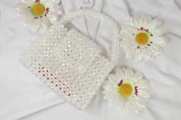 Handmade white purse made with bright beads on gray fabric with fake daisies flower. Top view.