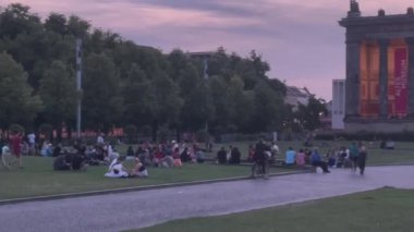 People rest on green lawn at dusk in Berlin, Germany