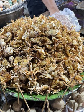 Büyük bir yığın kızarmış küçük yengeç veya mini yengeç koyu yeşil bir tepside servis edilir. Bu popüler sokak yemeğinin altın bir dokusu var..