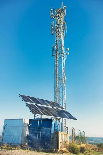 Mobile phone tower powered by solar panels, in the countryside.