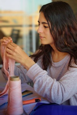 Tığ işi yapan konsantre genç bir kadın..