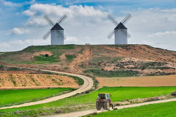 Bir tarım traktörü, ekin tarlaları ile eski Tembleque, Toledo (İspanya) yel değirmenlerinin heybetli figürünün altında toprak bir yolda dolaşır.),