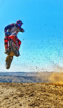 Casarrubios del Monte, Toledo / İspanya - 18 Eylül 2021: Arka planda mavi bir gökyüzü ile atlayan amatör bir motokros sürücüsünün görüntüsü.