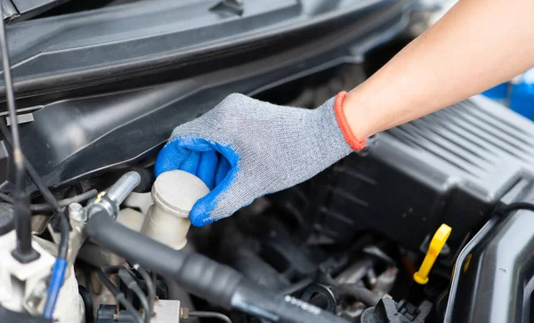 Car inspection and maintenance concept. Man checking brake fluid in engine room. Check car brake fluid for safe travel. Car Repairs, vehicle maintenance, car mechanic,
