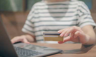 Dizüstü bilgisayar kullanan ve kredi kartı tutan bir kadın. finans ve çevrimiçi alışveriş kavramı, e-ticaret, internet bankacılığı, çevrimiçi ödeme, harcama parası,