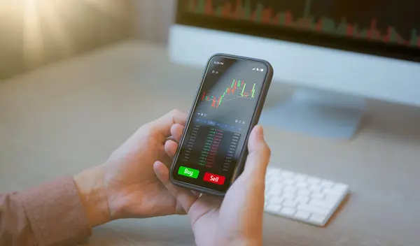 投資家とトレーダーの概念 アプリ分析を見てスマートフォンを保持しているビジネスマンやトレーダー投資家のアナリストの手株式取引所取引データシンボルを表示し — ストック写真