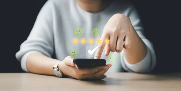 女性は5つ星を選び モバイルの周りに浮かぶ象徴的な感情的な笑顔を持っています 顧客レビュー満足度アンケートフィードバック調査の概念 ユーザーはオンラインアプリケーションでサービスエクスペリエンスに評価を与え 顧客はQを評価することができます — ストック写真