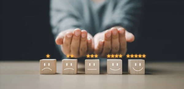 People's hands are choosing wooden blocks with one-star to five-star icons to choose from for service satisfaction. opinion poll Great review options Customer Service Rating.Text input area on hand.