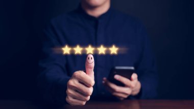 Elleri havada, duygu yüklü, gülümseyen yüz simgesi ve beş yıldızlı bir adam. Müşteri memnuniyet değerlendirmesi anket konsepti. Kullanıcı, akıllı telefon uygulamasında mükemmel bir deneyime sahip servise derecelendirme verir,