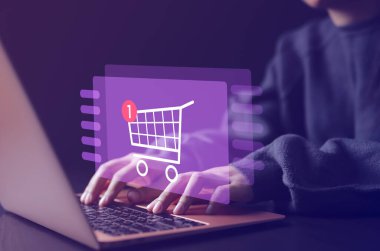 Çevrimiçi alışveriş ve e-ticaret teknolojisi internet kavramı. Alışveriş arabası simgesi olan bir dizüstü bilgisayar kullanan kadın ya da alışveriş sitesi internet üzerinden alışveriş yapan ya da internetten alışveriş yapan bir kadın.,