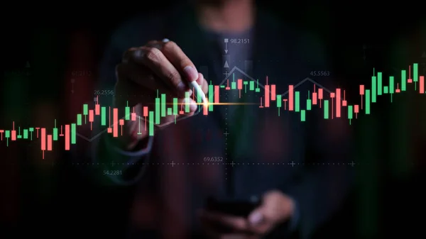 Bir işadamı veya tüccar büyüyen sanal bir hologram stoğuna işaret ediyor. Göstergeleri analiz etmek ve strateji alıp satmak. Borsa grafikleri, iş büyümesi, yatırım karı,