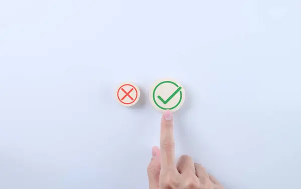 Approve and reject business proposal concept. Hand choosing right icon on white background. Symbol true and false on wooden block, Checkmark, x sign symbol, Red cross mark, Green correct sign mark,