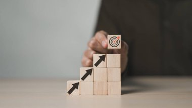 İş başarısı hedefi ve objektif hedef kavramı. İşadamı eli, tahta küp blokta ekranı gösteren sanal iş hedefi ve ok koyuyor. Büyüme yatırımları, Hedef Pazarlama Stratejileri,