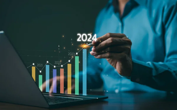 The 2024 New Year business goals concept. Businessman analyzes graph of trend market growth in 2024 and plans business growth and profit increases. calculates financial data for long-term investments.