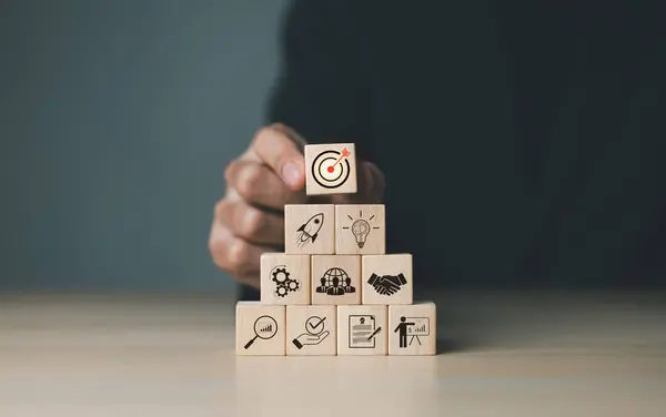 Business goals and target success concepts. Businessman places wooden blocks with business icons. business growth, Achievement company, corporate startup, investment goal, Planning ideas and strategy,