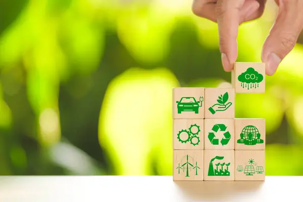 Carbon footprint concept. Hand put wooden cube with carbon reduction and green icon on nature background. Net zero carbon neutral, Carbon emissions, CO2 neutrality, Sustainable energy, Climate change,