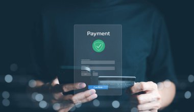 Güvenli Çevrimiçi Ödeme İşlem Süreci kavramı. Onaylama işareti olan dijital bir arayüz üzerinden kredi kartı kullanarak güvenli bir ödemeyi onaylayan kişi. İnternet bankacılığı, fintech,