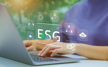 ESG sürdürülebilirlik hedefleri üzerinde çalışan bir kadın. Bir iş adamı dizüstü bilgisayarda ESG (Çevresel, Sosyal, Yönetim) sürdürülebilirlik kavramlarıyla ilgilenir. ESG raporu ve CSR kavramını analiz et.