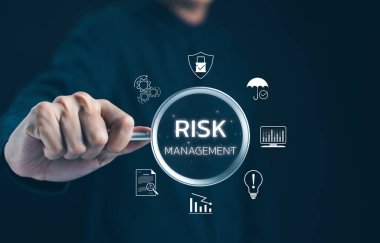 Profesyonel Risk İdaresi Konsepti. İşadamı risk yönetimi simgelerini vurgulayan bir büyüteç üzerinde durarak, iş risklerini en aza indirme stratejilerini vurguluyor. Risk değerlendirmesi,