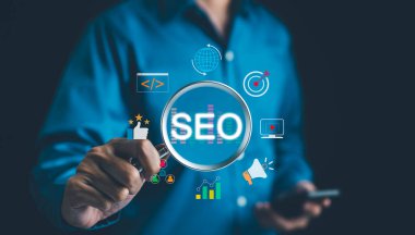 SEO Arama Motoru İyimserleştirme Konsepti. İş adamı, arama motoru optimizasyon stratejilerini temsil eden çeşitli dijital pazarlama simgeleriyle çevrili SEO 'yu vurgulayan büyüteç tutuyor.