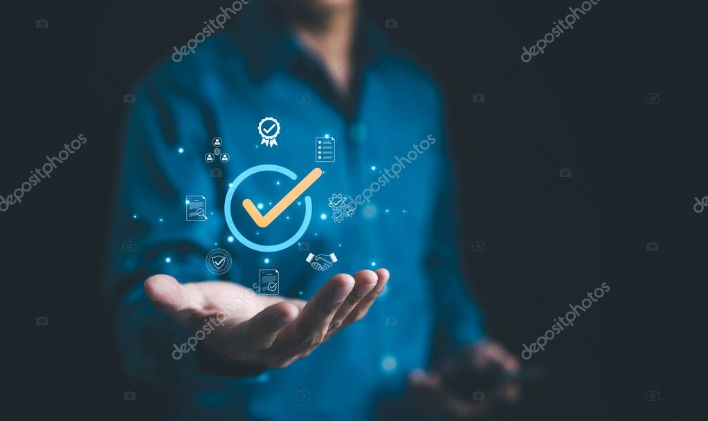 Businessman holding a digital icon of a checkmark with quality assurance and certification symbols, standard compliance and guarantee. quality control, automation process, Standardization management,