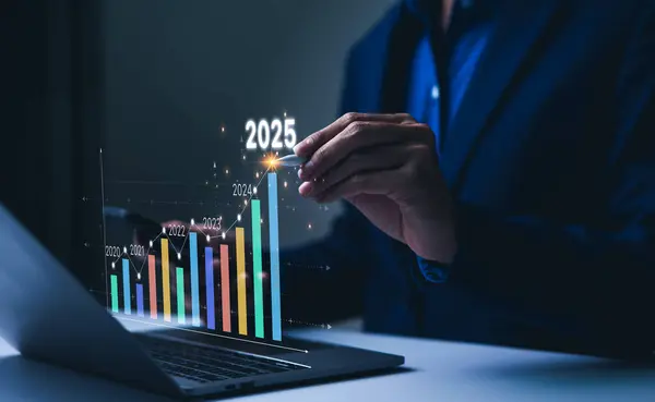 2025 Yılbaşı İş Hedefleri Konsepti. İşadamı 2025 yılındaki eğilimli pazar büyümesinin grafiğini analiz ediyor ve iş büyümesi ve kâr artışları planlıyor. Uzun vadeli yatırımlar için mali verileri hesaplar.