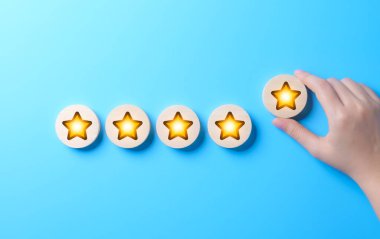 Müşteri memnuniyeti ve geri bildirim değerlendirme konsepti. Bir el, müşteri değerlendirmeleri, memnuniyeti ve kaliteli hizmetler veya ürünler için geri bildirim temsil eden parlayan yıldız sırasına beş yıldızlı bir not koyar.