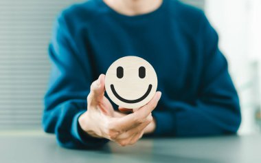 Pozitif zihniyet ve akıl sağlığı konsepti. Elinde ahşap gülücük sembolü, mutluluk, olumlu zihniyet, zihinsel sağlık farkındalığı ve müşteri memnuniyeti olan bir adam. duygusal refah ve iyimserlik,