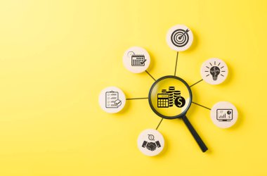 Bütçe Planlama ve Mali Yönetim Konsepti. Hesap makinesi, madeni para ve takvim gibi finans ikonları üzerindeki büyüteç, bütçe planlamasını, finansal analizi ve ekonomik hedef belirlemeyi simgeliyor.