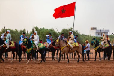 Essaouira, Fas - 13 Ağustos 2023: Biniciler geleneksel Fas kıyafeti ve şövalyelerin aksesuarları içinde Arapça Tbourida adlı geleneksel bir giysi etkinliğine katılıyorlar